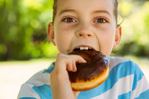 Мила дівчинка їсть пончик — стокове фото