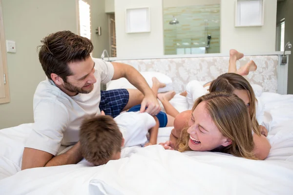 Счастливая семья, играющая на кровати — стоковое фото