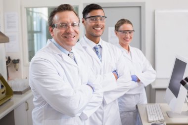 Smiling scientists looking at camera arms crossed clipart