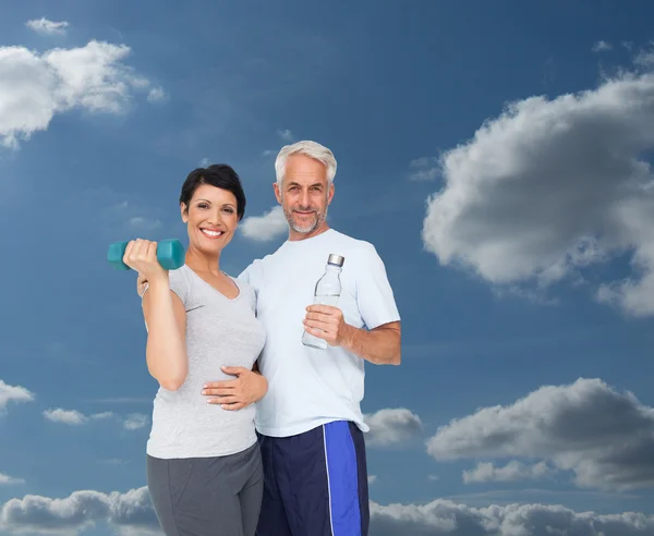 Pareja adecuada con mancuerna y botella de agua —  Fotos de Stock