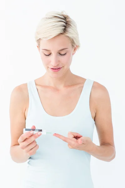 Pretty blonde testing her blood glucose level — Stock Photo, Image