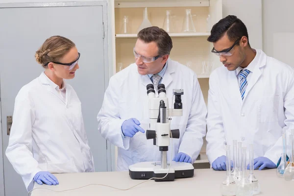 Científicos concentrados trabajando juntos con microscopio —  Fotos de Stock