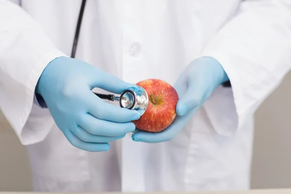 Ученый слушает яблоко со стетоскопом — стоковое фото