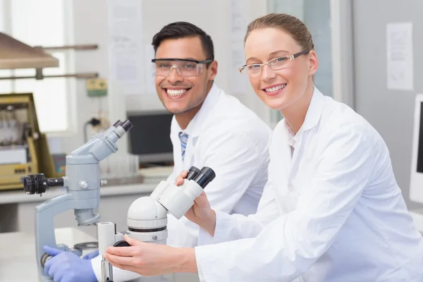 Happy scientists using microscope — Stock Photo, Image