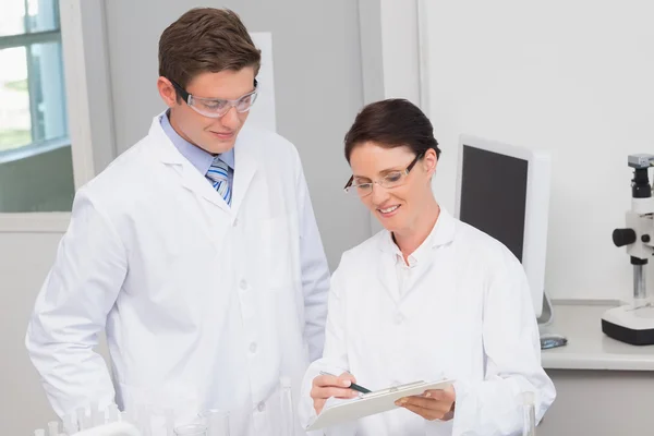 Smiling scientists looking at clipboard — Stock Photo, Image