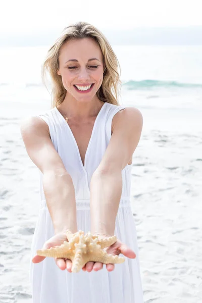 Blonde in white dress holding starfish — Stock Photo, Image