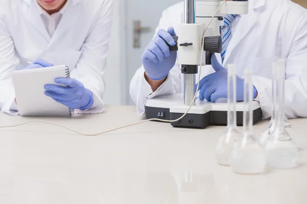 Científicos examinando algo con el microscopio — Foto de Stock