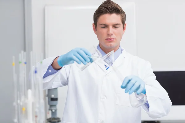 Cientista derramando produto químico em funil — Fotografia de Stock