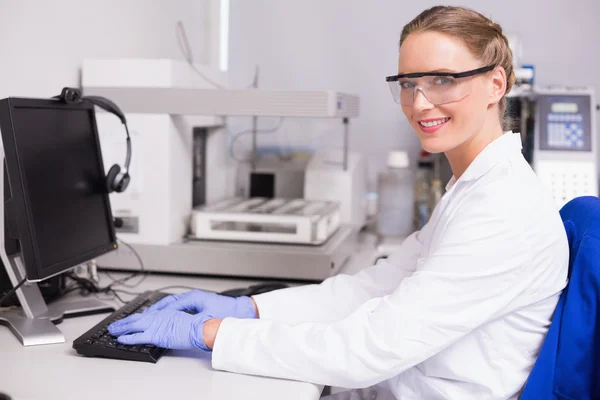 Cientista olhando para a câmera e usando o computador — Fotografia de Stock