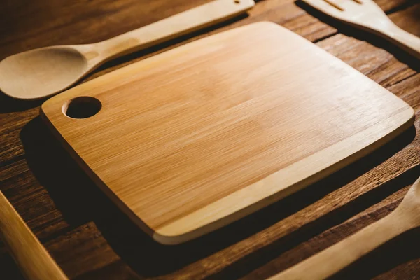 Chopping board with wooden utensils — Stock Photo, Image