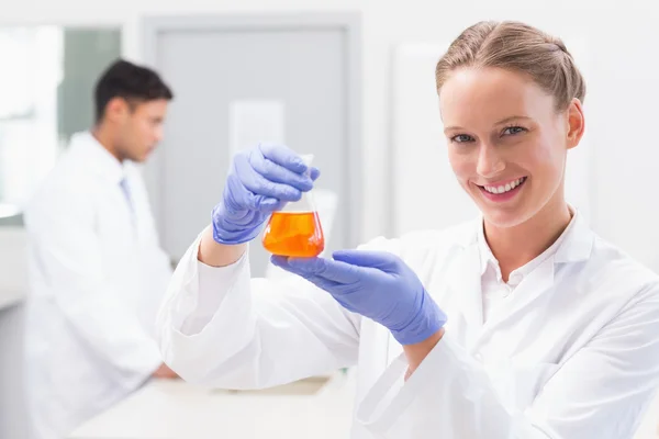 Científico sosteniendo vaso de precipitados con líquido naranja — Foto de Stock