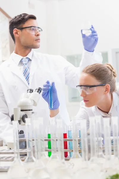 Wissenschaftler untersuchen Reagenzglas und Becher — Stockfoto