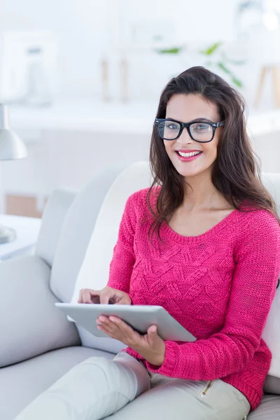 Lächelnde schöne Brünette mit ihrem Tablet auf der Couch — Stockfoto