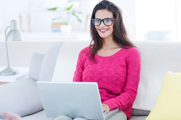 Glimlachend mooie brunette met behulp van haar laptop op de Bank — Stockfoto