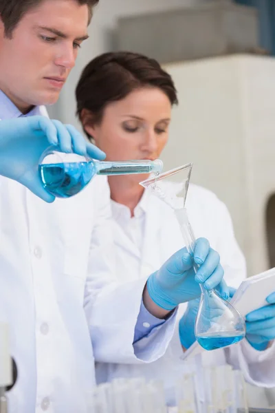 Cientistas derramando fluido químico em funil — Fotografia de Stock