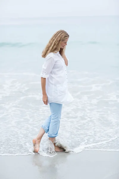 Blonde souriante marchant au bord de la mer — Photo