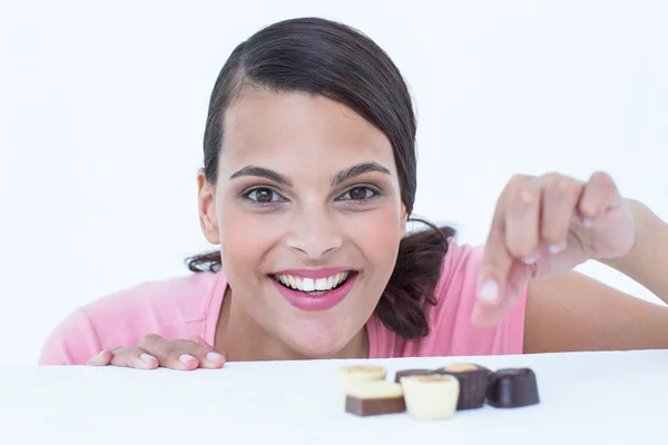 Hübsche Brünette guckt auf Schokolade und schaut in die Kamera — Stockfoto