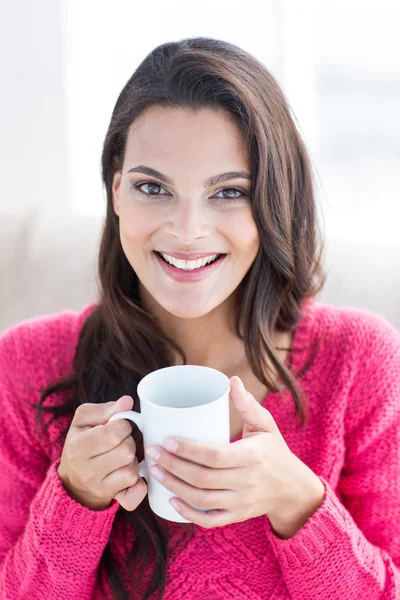 Sorrindo bela morena relaxante no sofá e segurando caneca — Fotografia de Stock