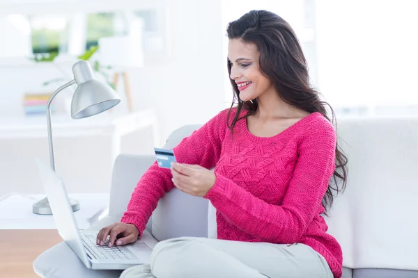 Lachende mooie brunette doen online winkelen op de Bank — Stockfoto