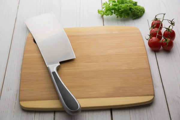 Tábua de corte com faca grande e ingredientes — Fotografia de Stock