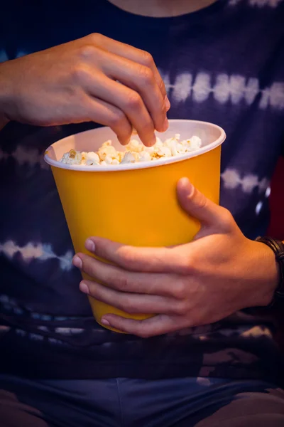 Mladý muž sleduje film a jíst popcorn — Stock fotografie