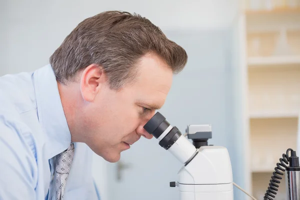 Científico examinando la muestra con microscopio — Foto de Stock