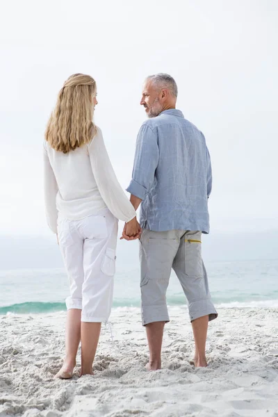 Счастливая пара, держащаяся за руки на пляже — стоковое фото