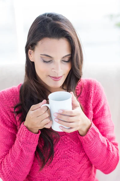 Smiling beautiful brunette relaxing on the couch and holding mug — Stock Photo, Image