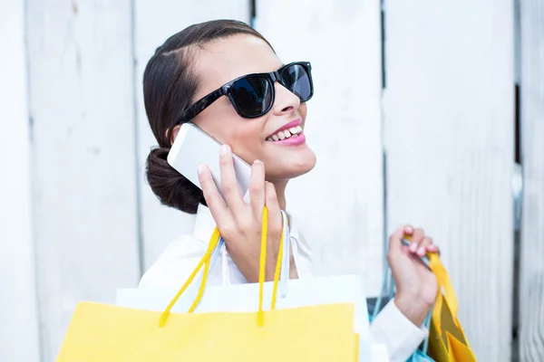 Mujer bonita en el teléfono sosteniendo bolsas de compras — Foto de Stock