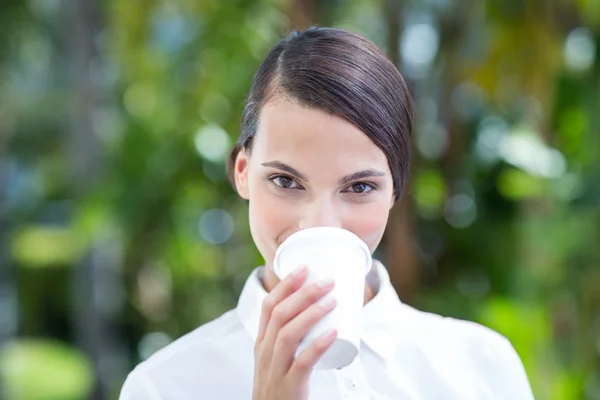 Pretty brunette drinking coffee and looking at camera — Stock Photo, Image