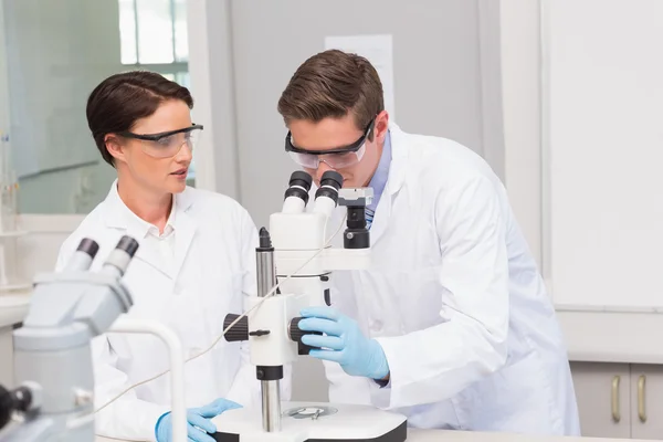 Scientists looking attentively in microscope — Stock Photo, Image