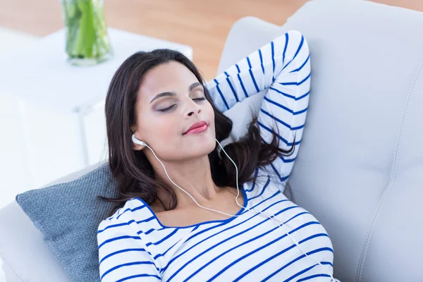 Gülümseyen güzel esmer kanepe ve dinleme m üzerinde rahatlatıcı — Stok fotoğraf