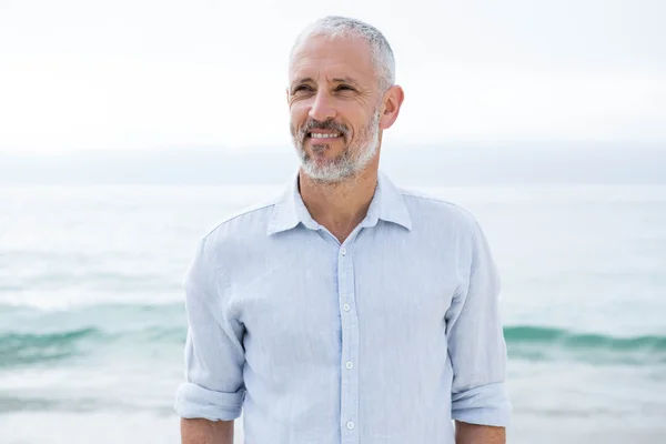 Uomo sorridente in piedi vicino al mare — Foto Stock