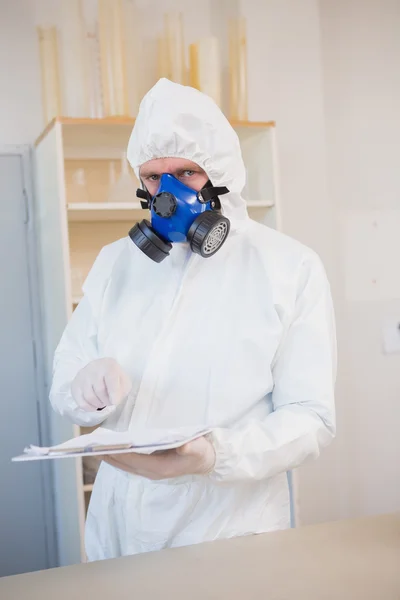 Scientist in protective suit pointing clipboard — Stock Photo, Image