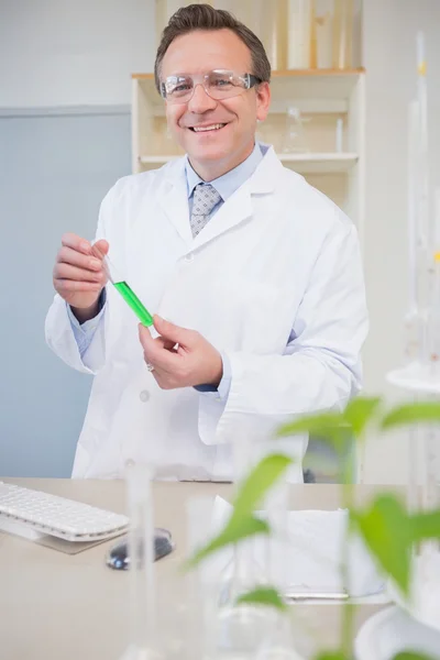 Científico sonriendo a cámara sosteniendo tubo — Foto de Stock