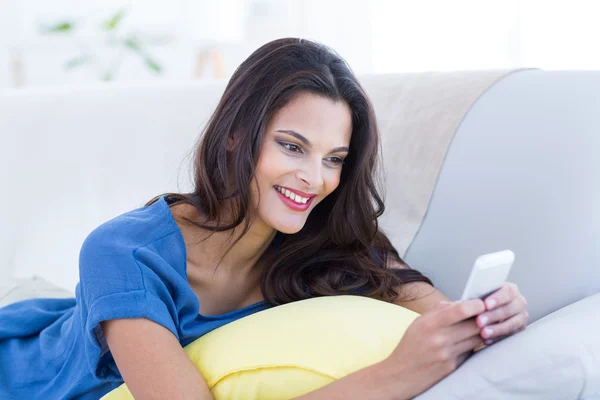 Lächelnd schön brünette relaxen auf der couch — Stockfoto