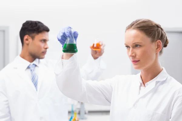 Concentrated scientists holding beakers with fluid — Stock Photo, Image
