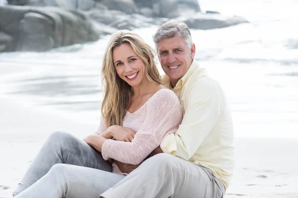 Feliz casal sentado na areia — Fotografia de Stock