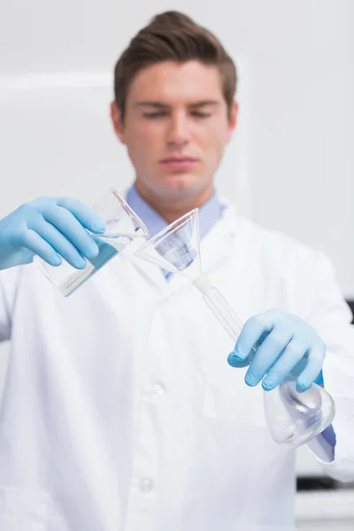 Cientista derramando produto químico em funil — Fotografia de Stock