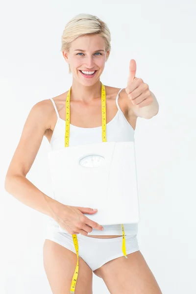 Mujer feliz sosteniendo escamas con pulgares arriba — Foto de Stock