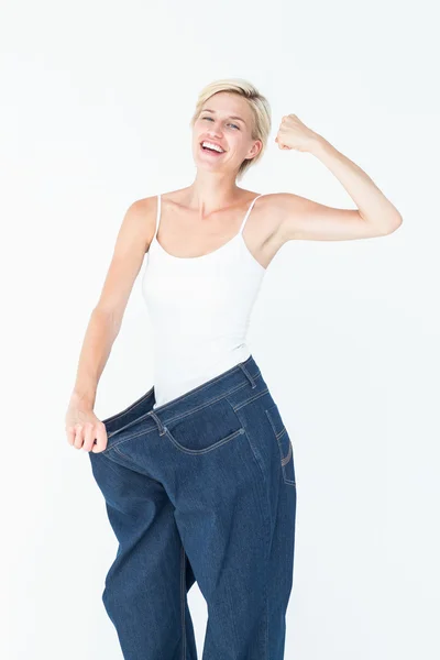 Mujer sonriente usando vaqueros demasiado grandes —  Fotos de Stock