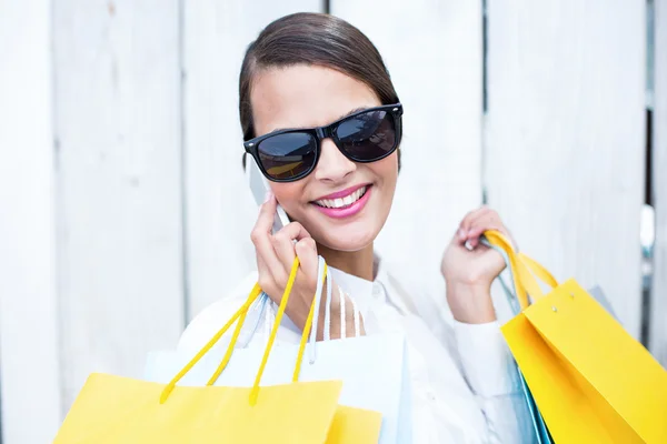 Mooie vrouw op de telefoon houden shopping tassen — Stockfoto