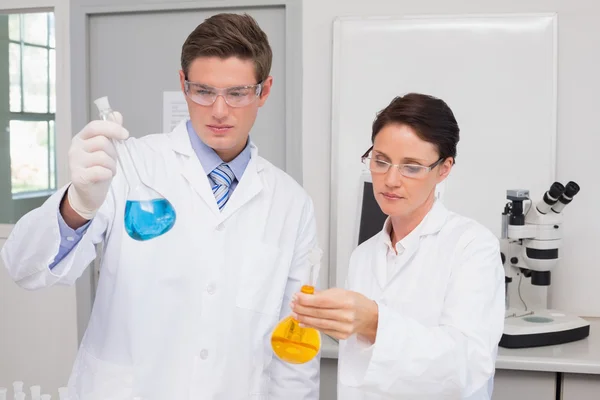 Wissenschaftler schauen aufmerksam auf Becher — Stockfoto