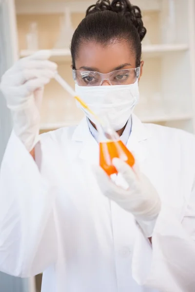 Koncentrerad vetenskapsmannen undersöker orange vätska — Stockfoto