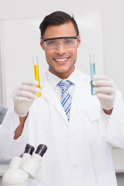 Cientista sorridente examina precipitados em tubos — Fotografia de Stock