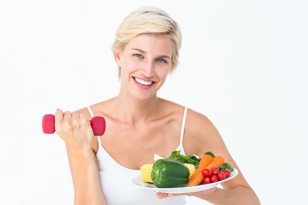 Attractive woman holding vegetables plate and dumbbell Royalty Free Stock Photos