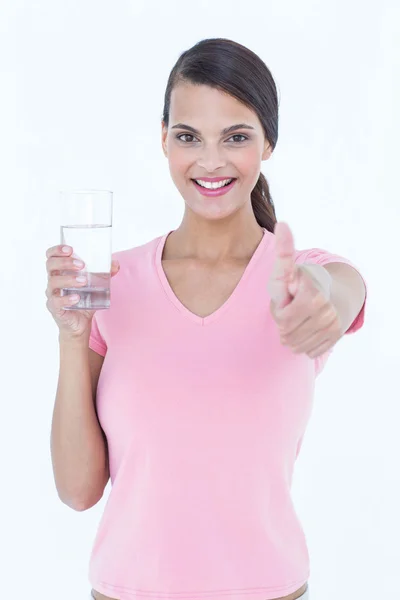 Mooie vrouw drinken glas water met duim omhoog — Stockfoto