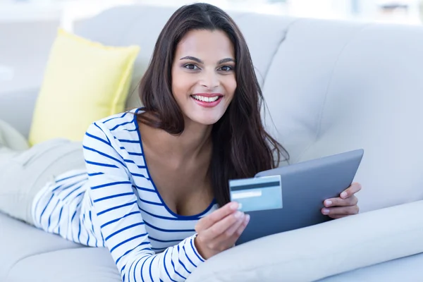 Uśmiechnięta brunetka robi zakupy online na kanapie — Zdjęcie stockowe