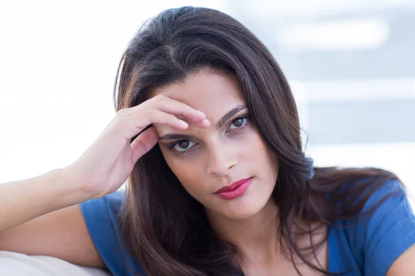 Nachdenklich schöne Brünette sitzt auf der Couch — Stockfoto