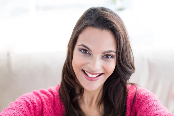 Smiling beautiful brunette relaxing on the couch and looking at — Stock Photo, Image